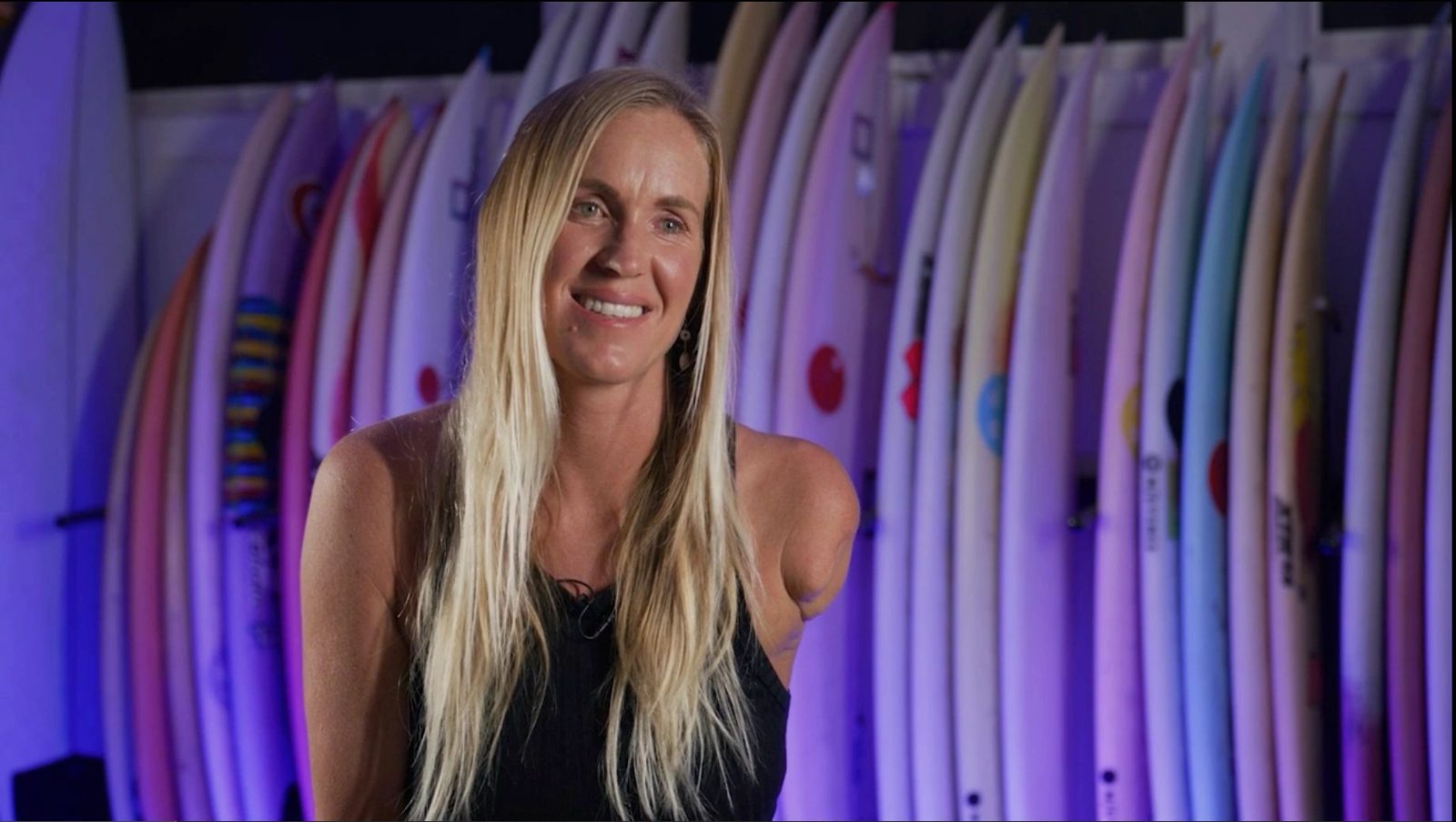Bethany Hamilton in front of a rack of surfboards